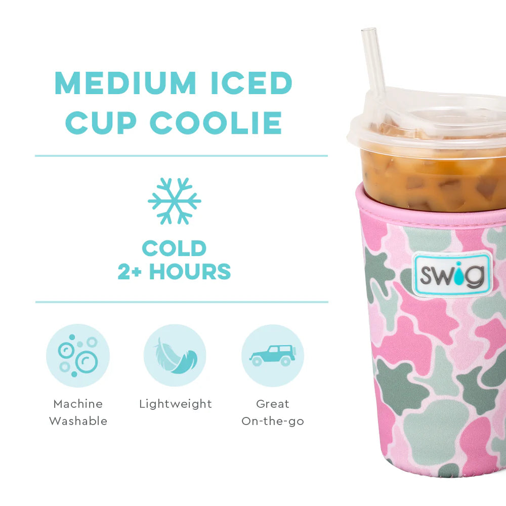 Swig Life Medium Iced Cup Coolie in Blushing Camo print, featuring pink, light green, and white abstract camo shapes, shown holding a clear plastic cup of iced coffee with straw alongside text highlighting features.