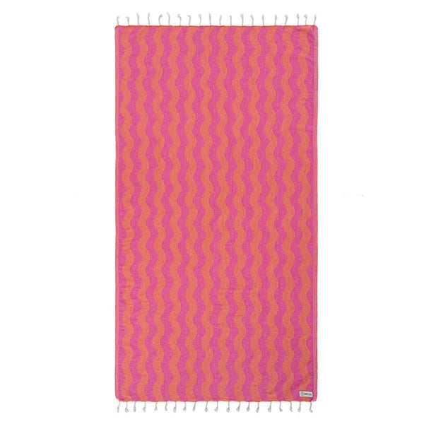 Pink and orange wavy patterned Sand Cloud towel with white tassels on a white background