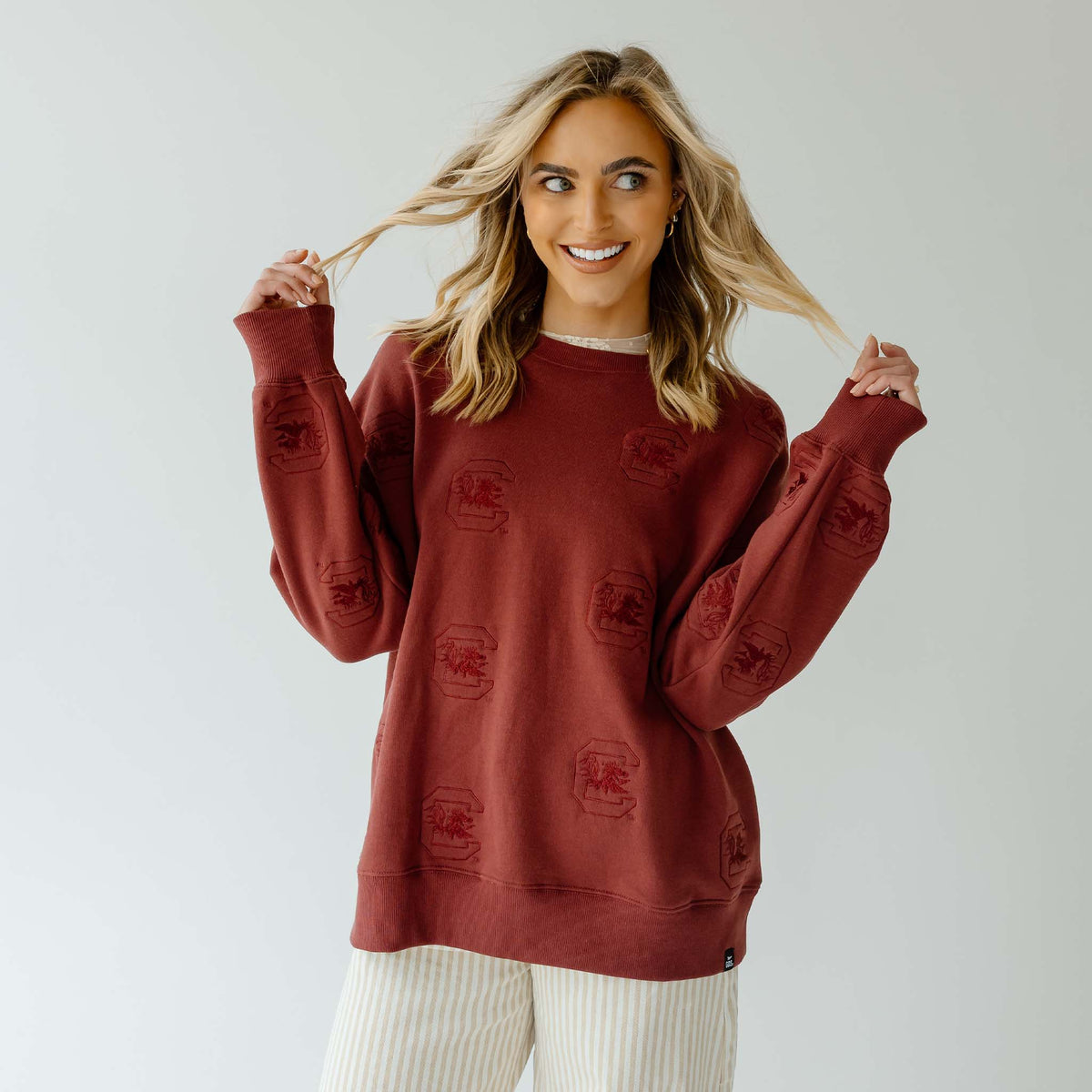 Woman wearing maroon University of South Carolina crewneck sweatshirt with tonal Gamecock logos throughout.