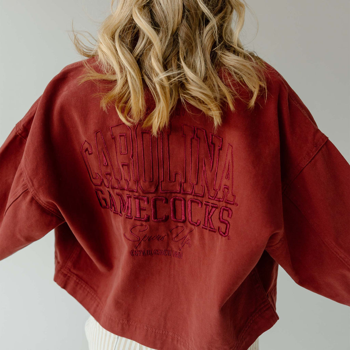 Maroon cropped jacket with large embroidered “Carolina Gamecocks Spurs Up” lettering across the back.