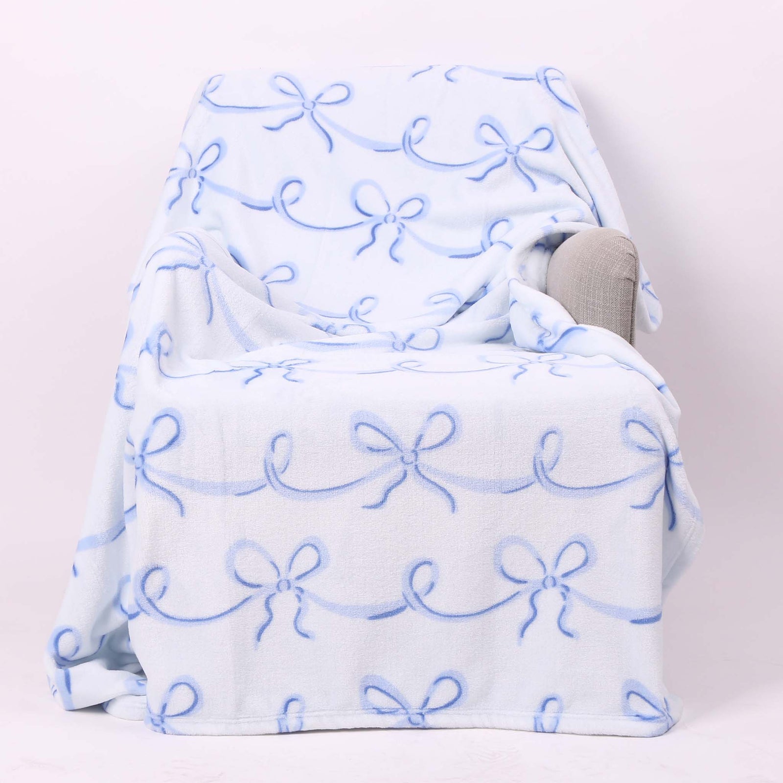 Blue bow printed fleece blanket shown laid across a chair.