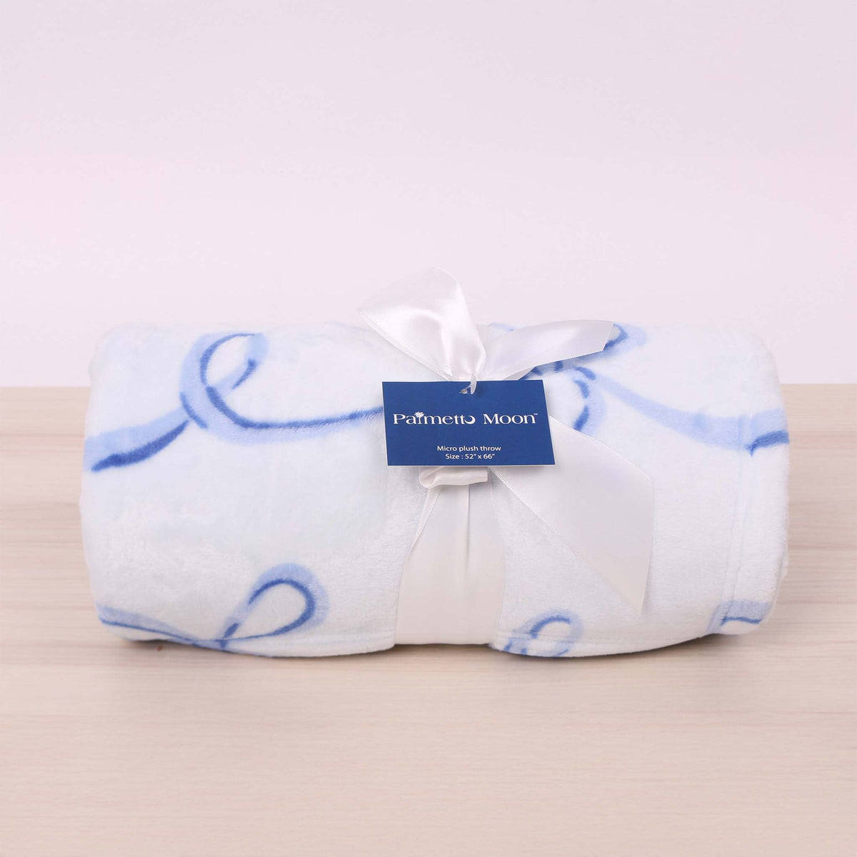 Blue bow printed fleece blanket shown rolled up and tied with a bow.