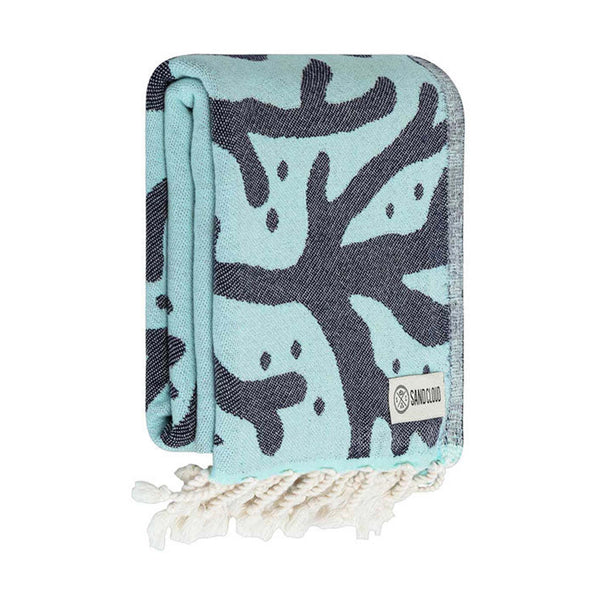 Folded towel with coral reef pattern and Sand Cloud label on a white background