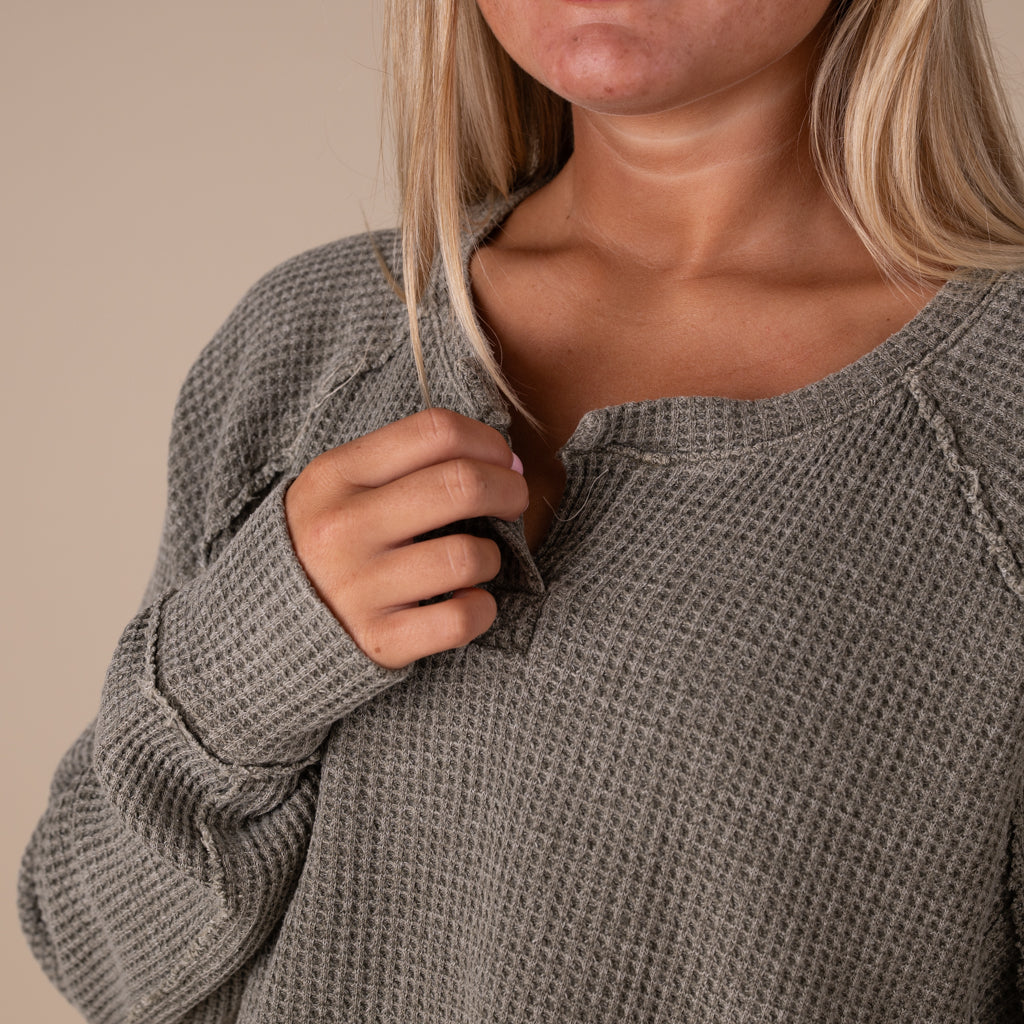 Person wearing a textured gray sweater against a beige background