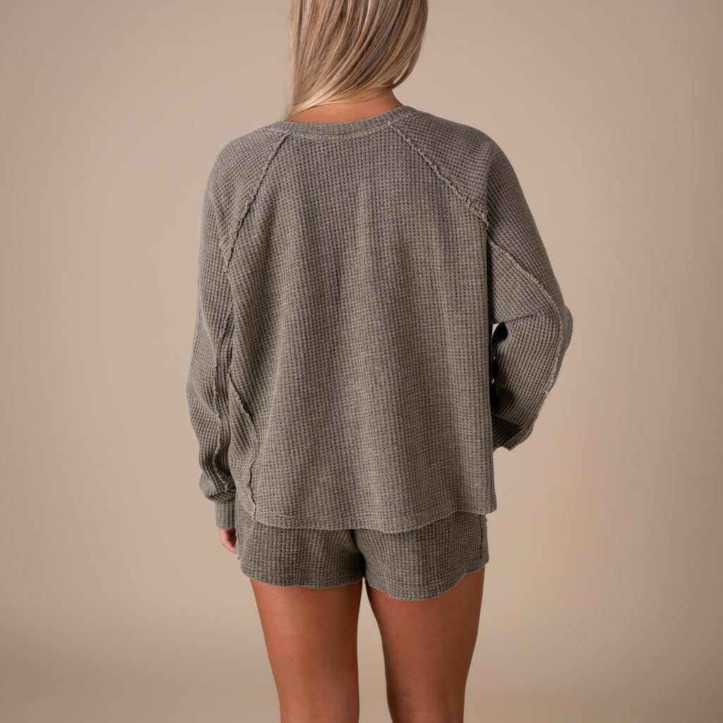 Person wearing a gray waffle knit outfit on a beige background