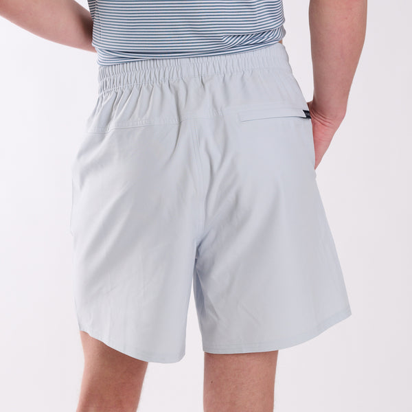 Man wearing light gray shorts and a striped shirt on a white background.
