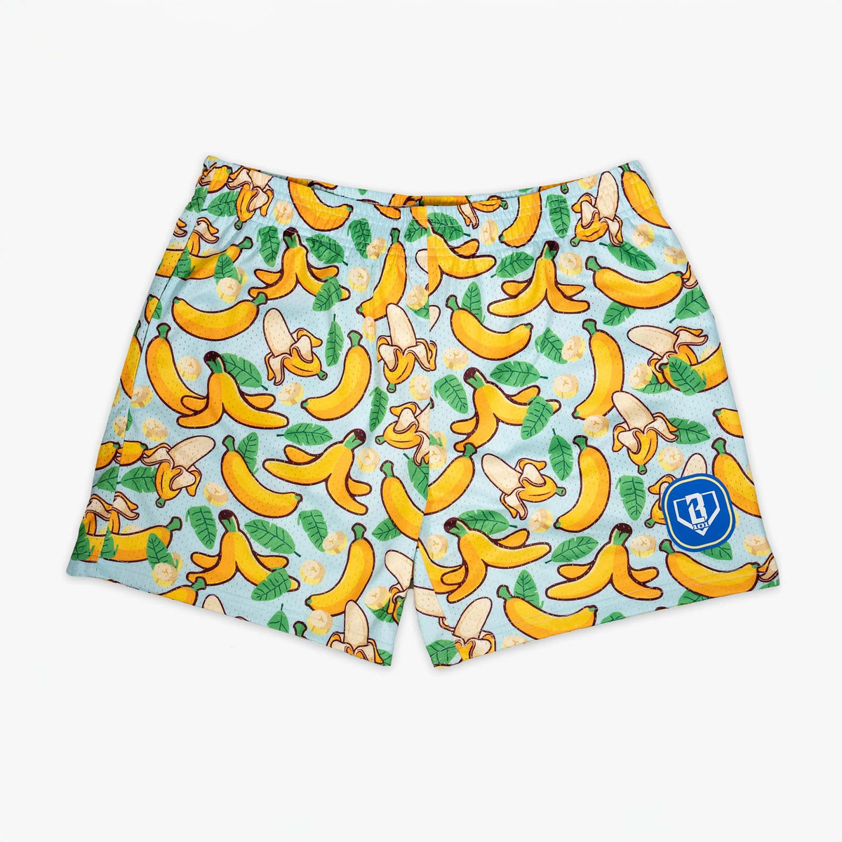 Flat lay of Baseball Lifestyle 101 Youth Shorts with all over banana and tropical leaf pattern on a light blue background