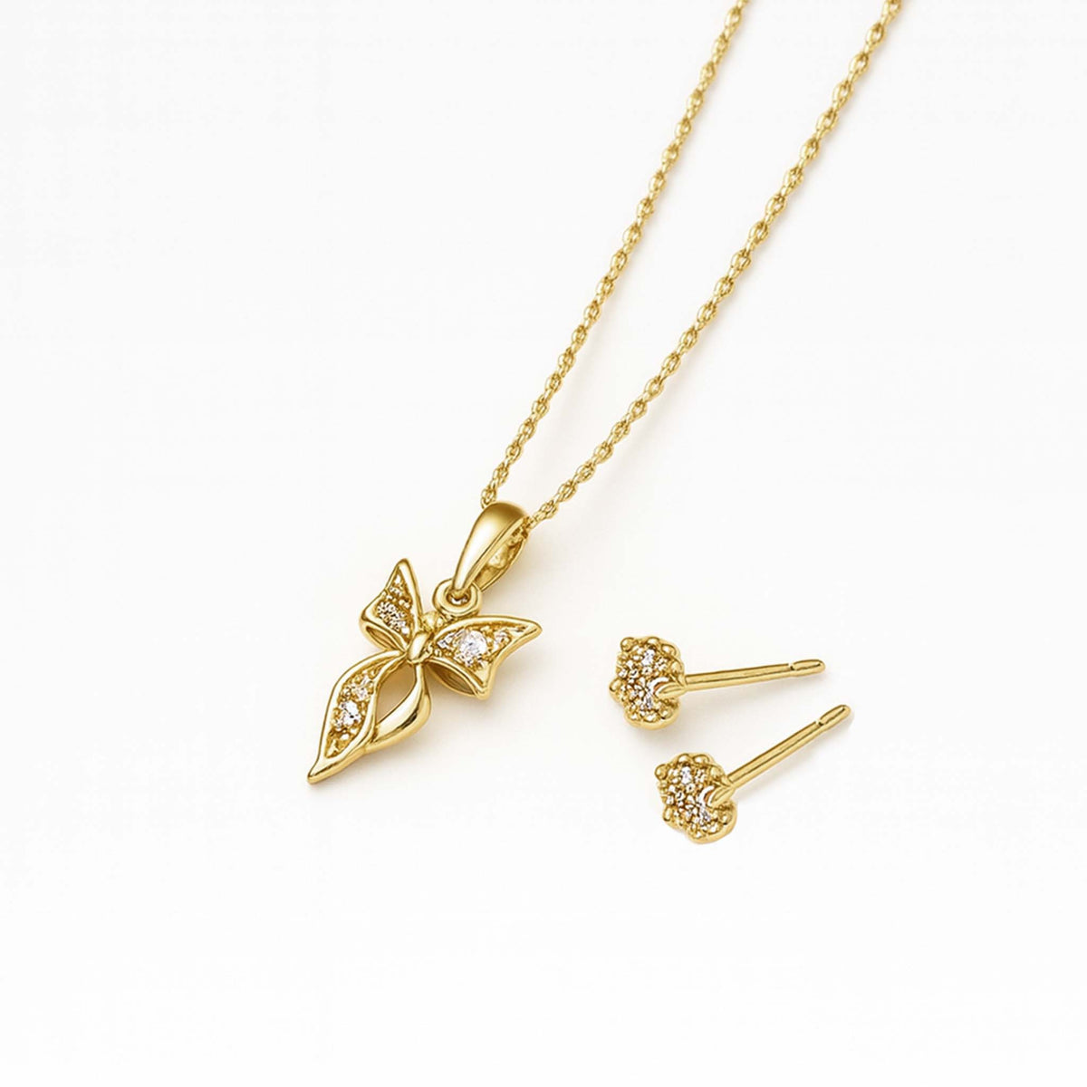 Gold bow pendant necklace with cubic zirconia shown beside matching CZ stud earrings on a clean white background.