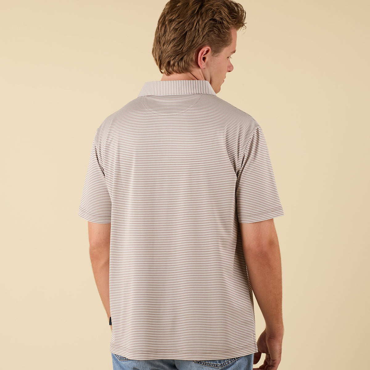 Man wearing a striped polo shirt on a beige background