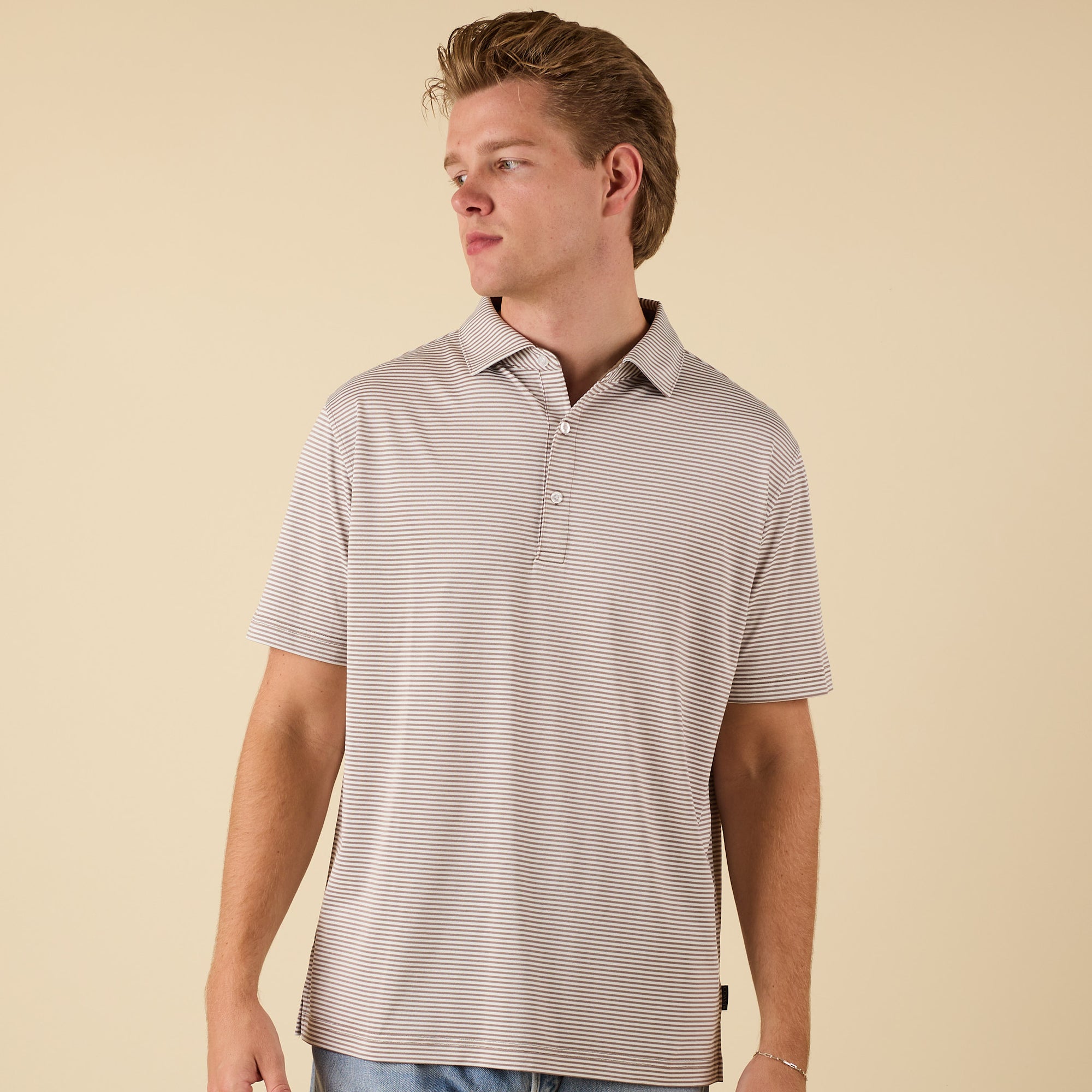 Man wearing a striped polo shirt against a beige background
