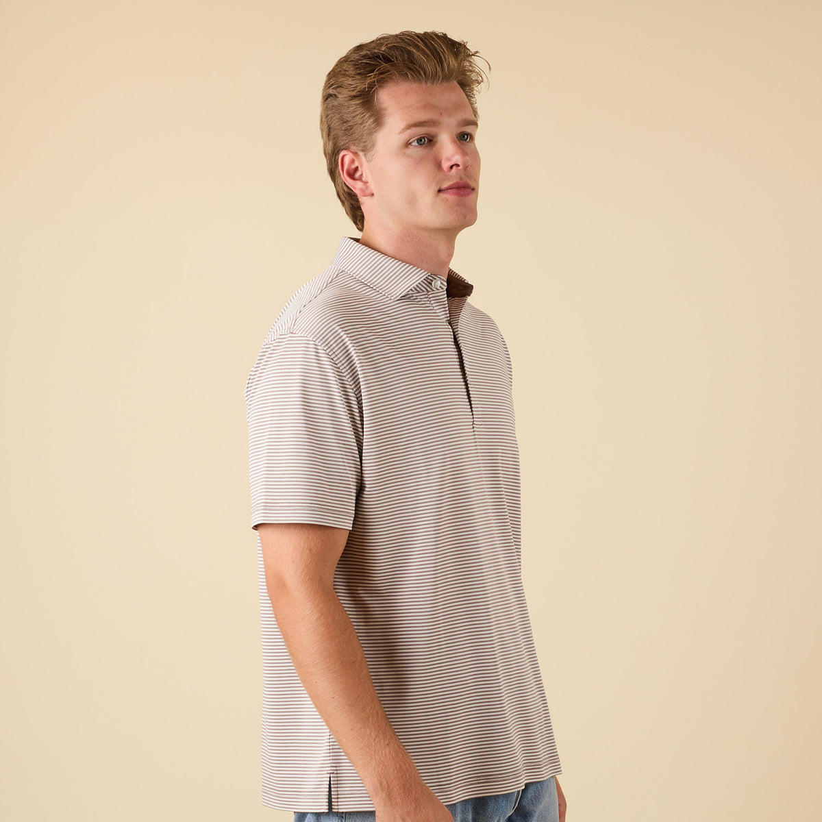 Man wearing a striped polo shirt against a beige background