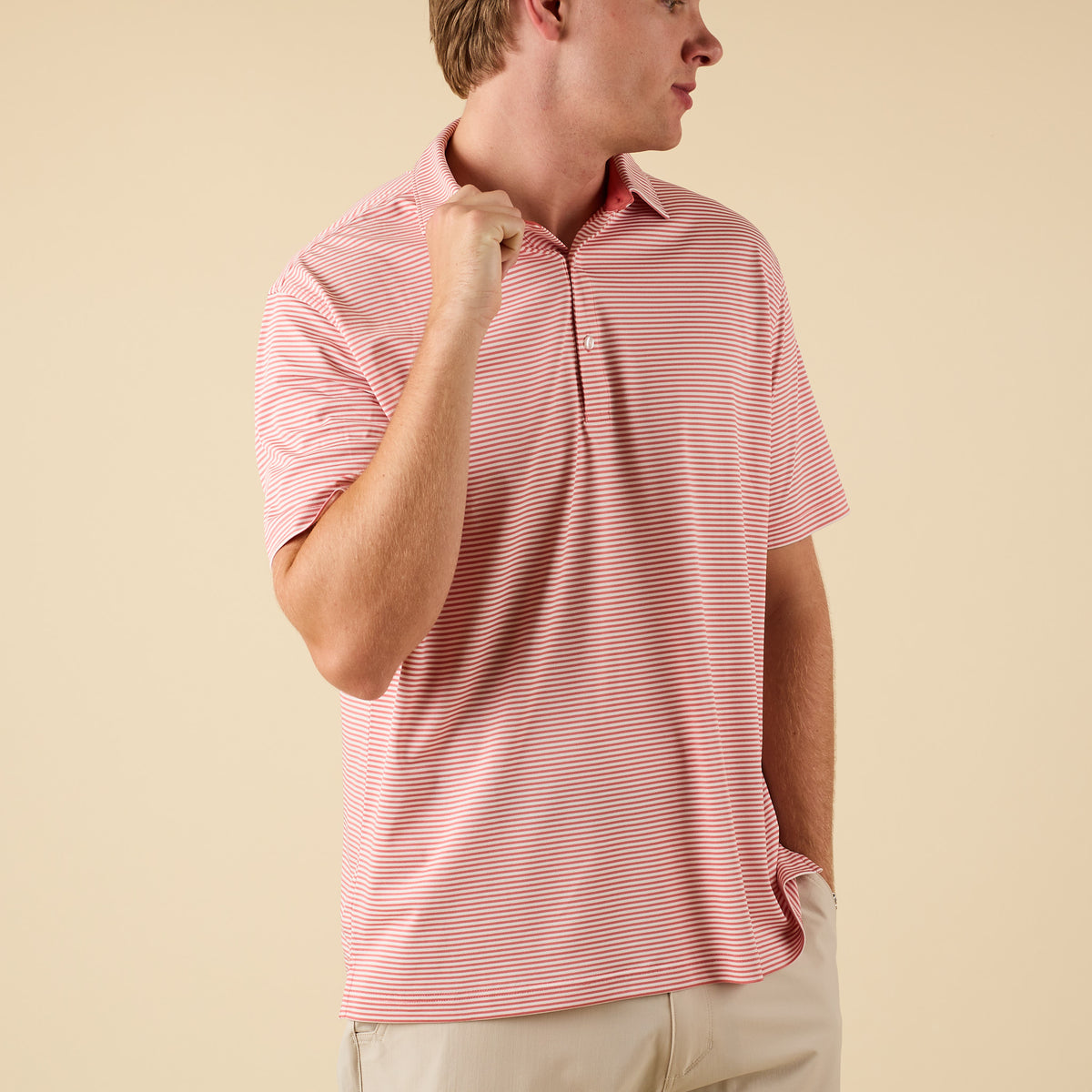 Man wearing a pink striped polo on a beige background.