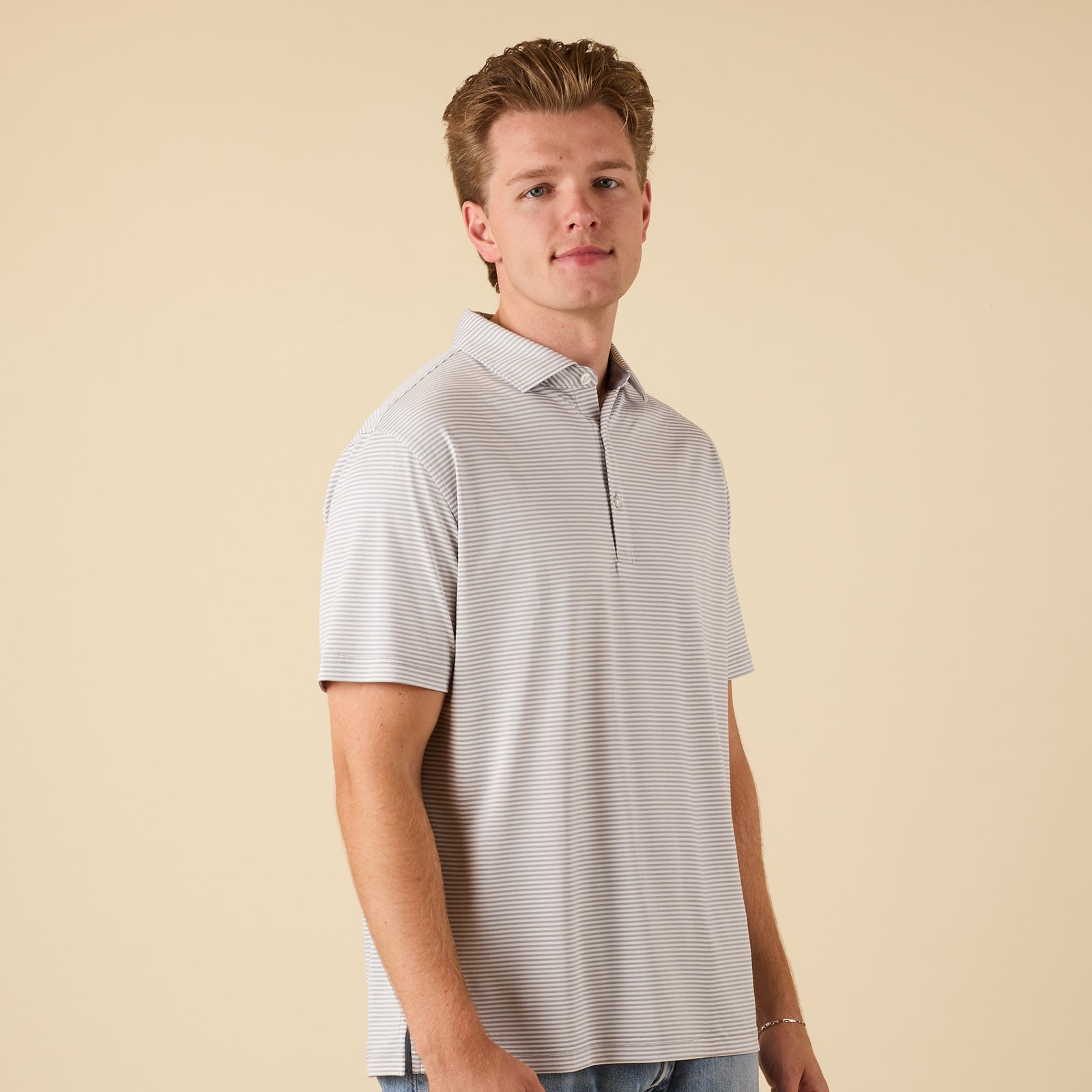 Man wearing a striped polo shirt against a beige background