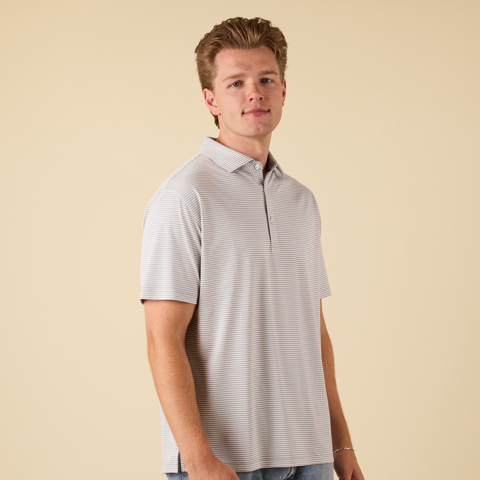 Man wearing a striped polo shirt against a beige background