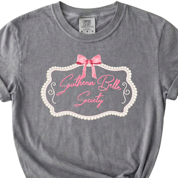 Close-up of grey Southern Belle Society t-shirt featuring pink script text inside a pearl-trimmed frame with a pink bow graphic.