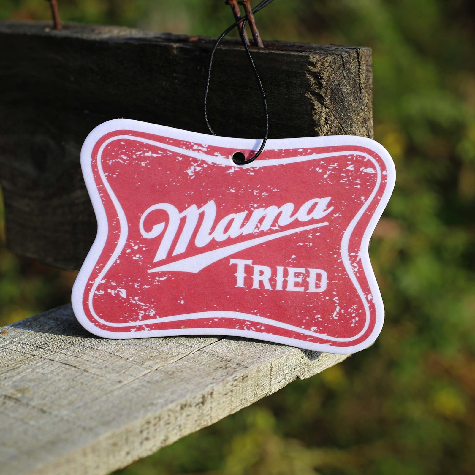 Scent South red distressed air freshener with “Mama Tried” text in white script, hanging outdoors.