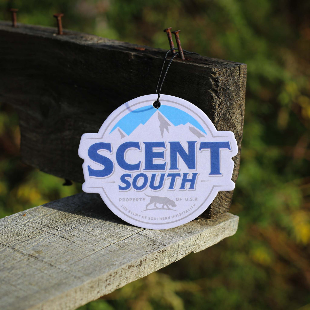 Scent South air freshener with blue mountain logo and “Scent South” branding in bold letters, hanging from a string.