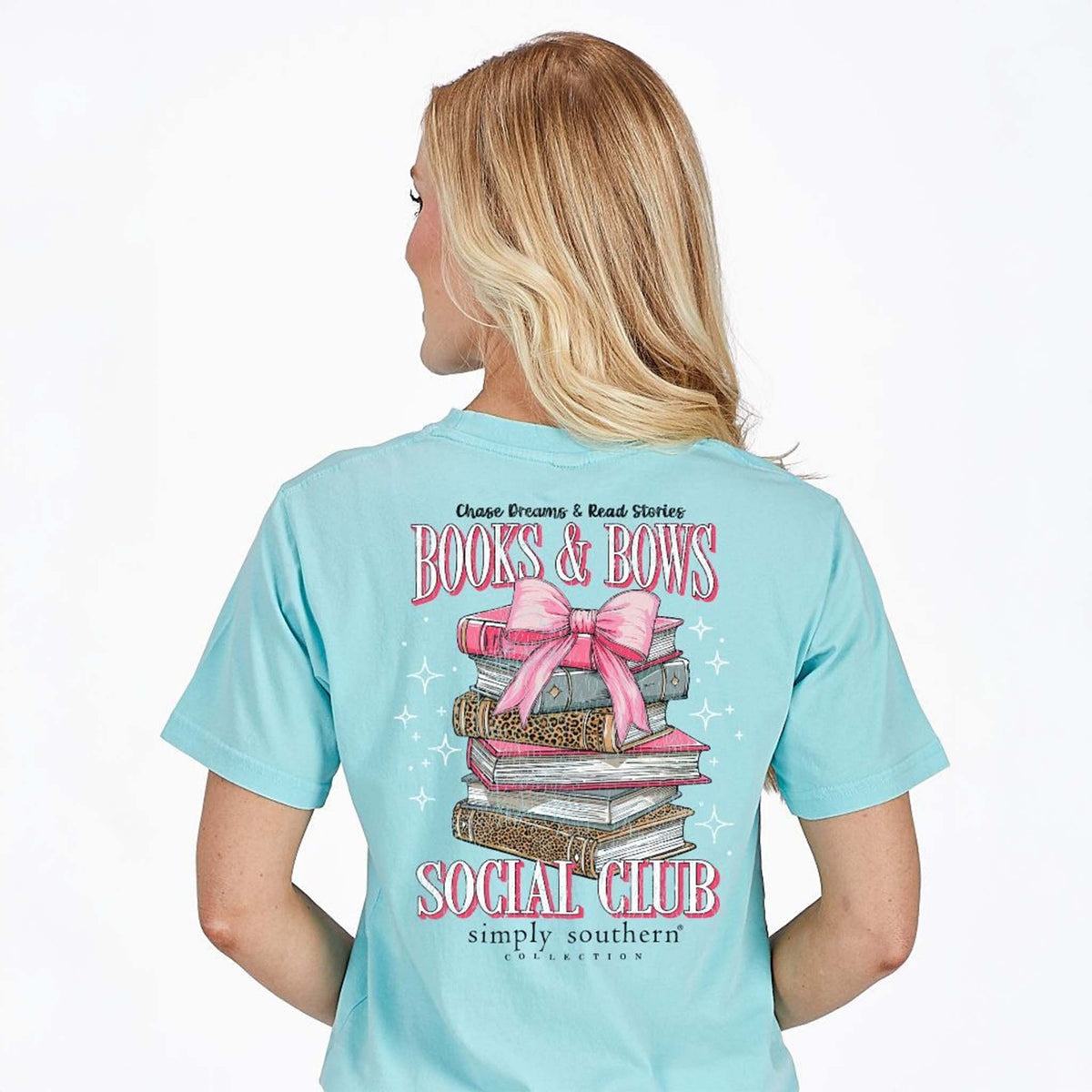 Woman wearing a light blue t-shirt with 'Books & Bows Social Club' design on the back.