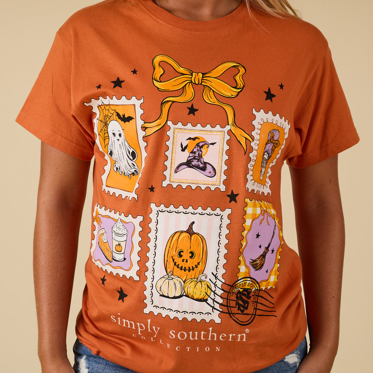 Close-up of caramel Simply Southern short sleeve tee with Halloween stamp artwork featuring pumpkins, ghost, witch hat, and seasonal icons.