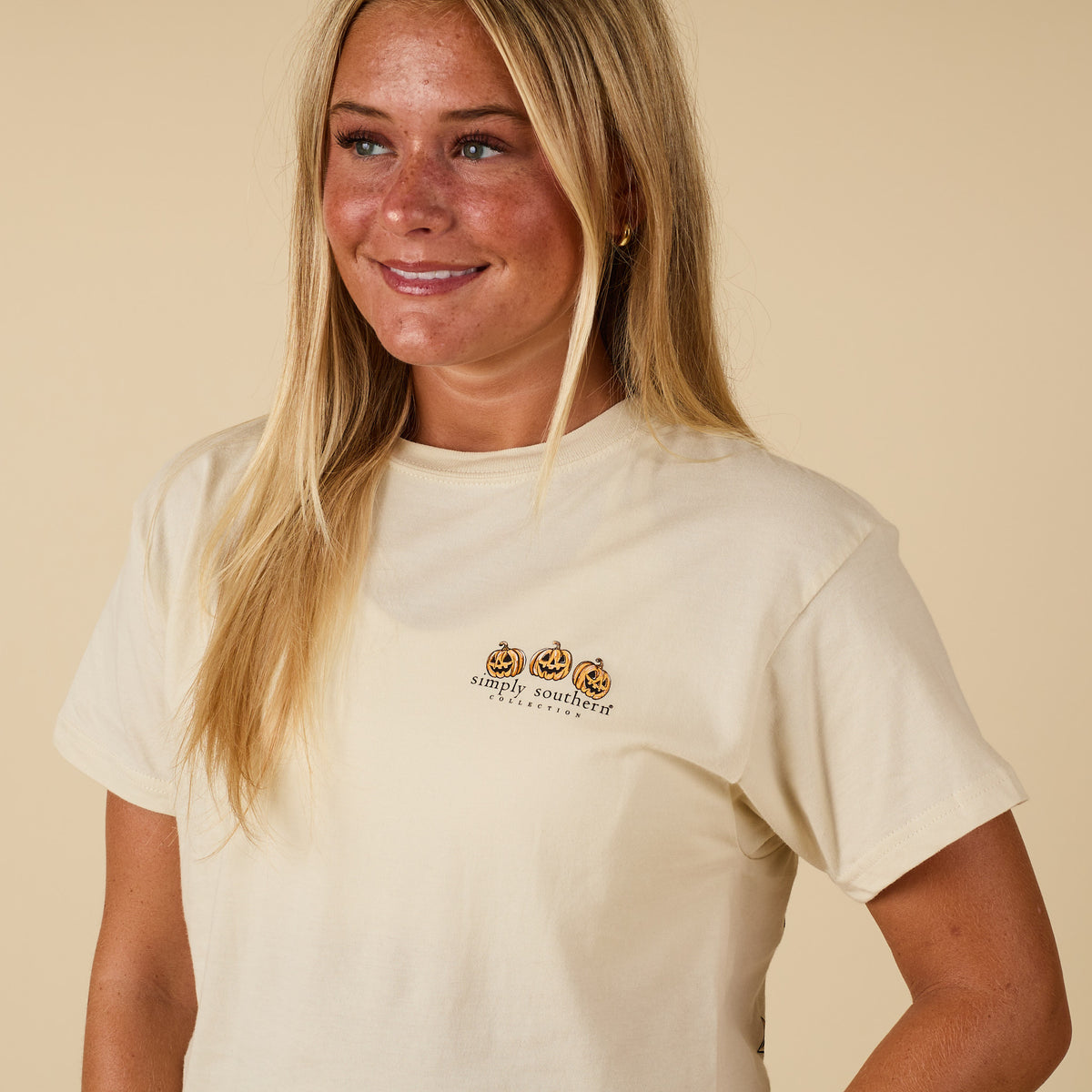Front of ivory Simply Southern short sleeve tee with three jack-o’-lantern pumpkins and Simply Southern logo.