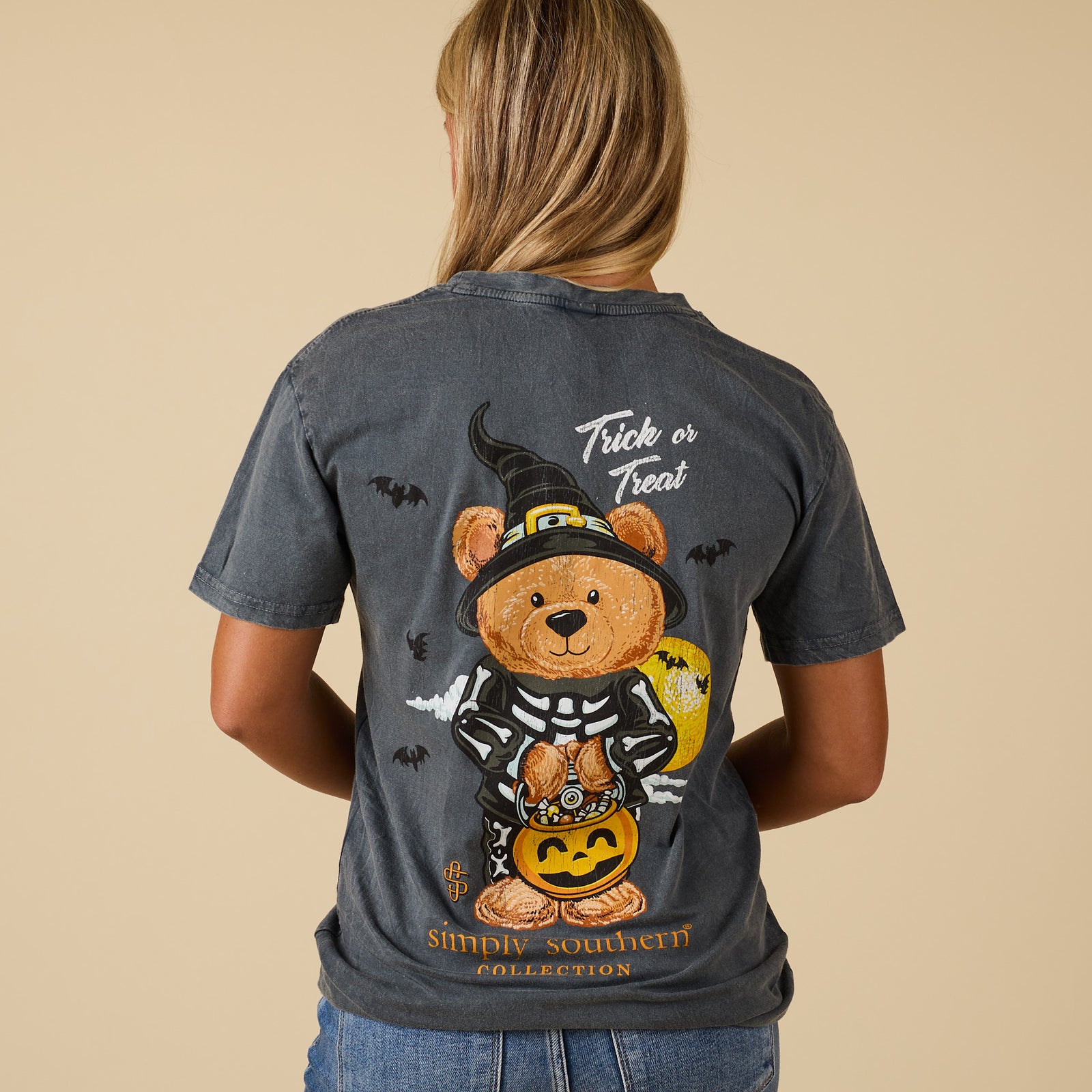 Back of washed coal Simply Southern short sleeve tee with teddy bear in skeleton costume and witch hat holding pumpkin candy bucket, “Trick or Treat” text above.