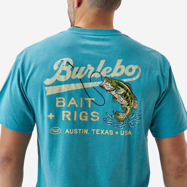 Close-up of the back graphic on a teal short sleeve t-shirt showing “Burlebo Bait + Rigs Austin, Texas USA” text with a largemouth bass and fishing hook illustration.