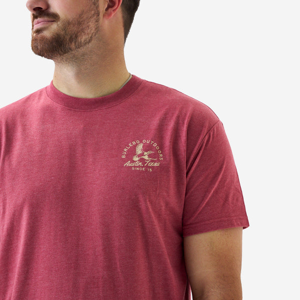 Close-up of a heather red short sleeve Burlebo t-shirt showing the small chest graphic with duck illustration and “Austin, Texas Since ’15” text.