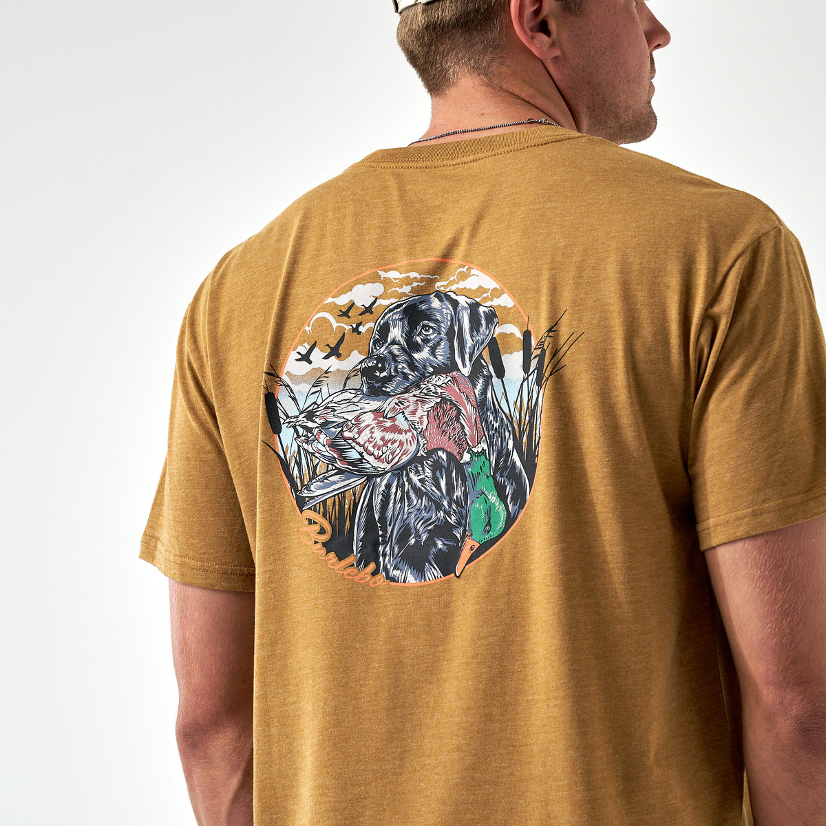 Back view of light brown Burlebo tee featuring a black lab holding a duck in hunting scene.