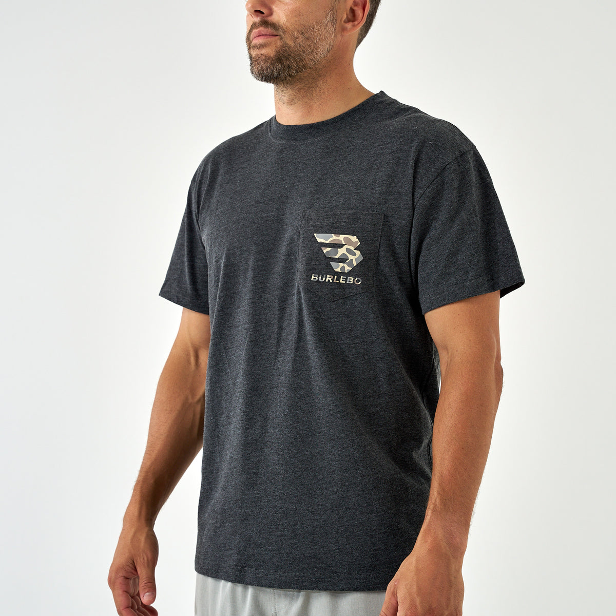 Man wearing a dark charcoal short sleeve t-shirt with a chest pocket featuring a light brown camo Burlebo logo.