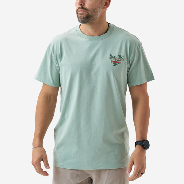 Front view of a male model wearing a sage green short sleeve Burlebo t-shirt with a small chest logo that reads “Burlebo Outdoors” with flying duck silhouettes.