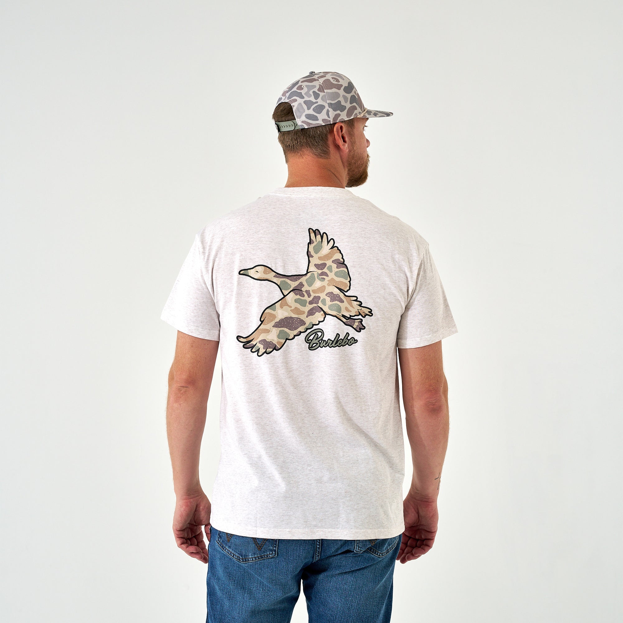 Light oat t-shirt with large camo duck graphic and "Burlebo" text on back, man wearing jeans and camo cap, rear view.