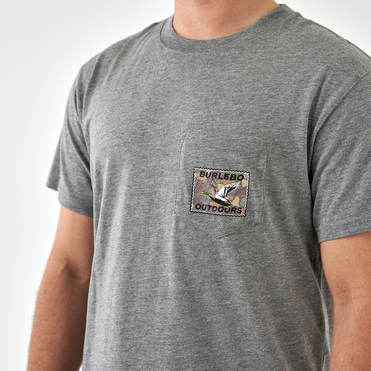 Front view of dark heather gray short sleeve pocket t-shirt with Burlebo Outdoors duck stamp graphic on pocket.