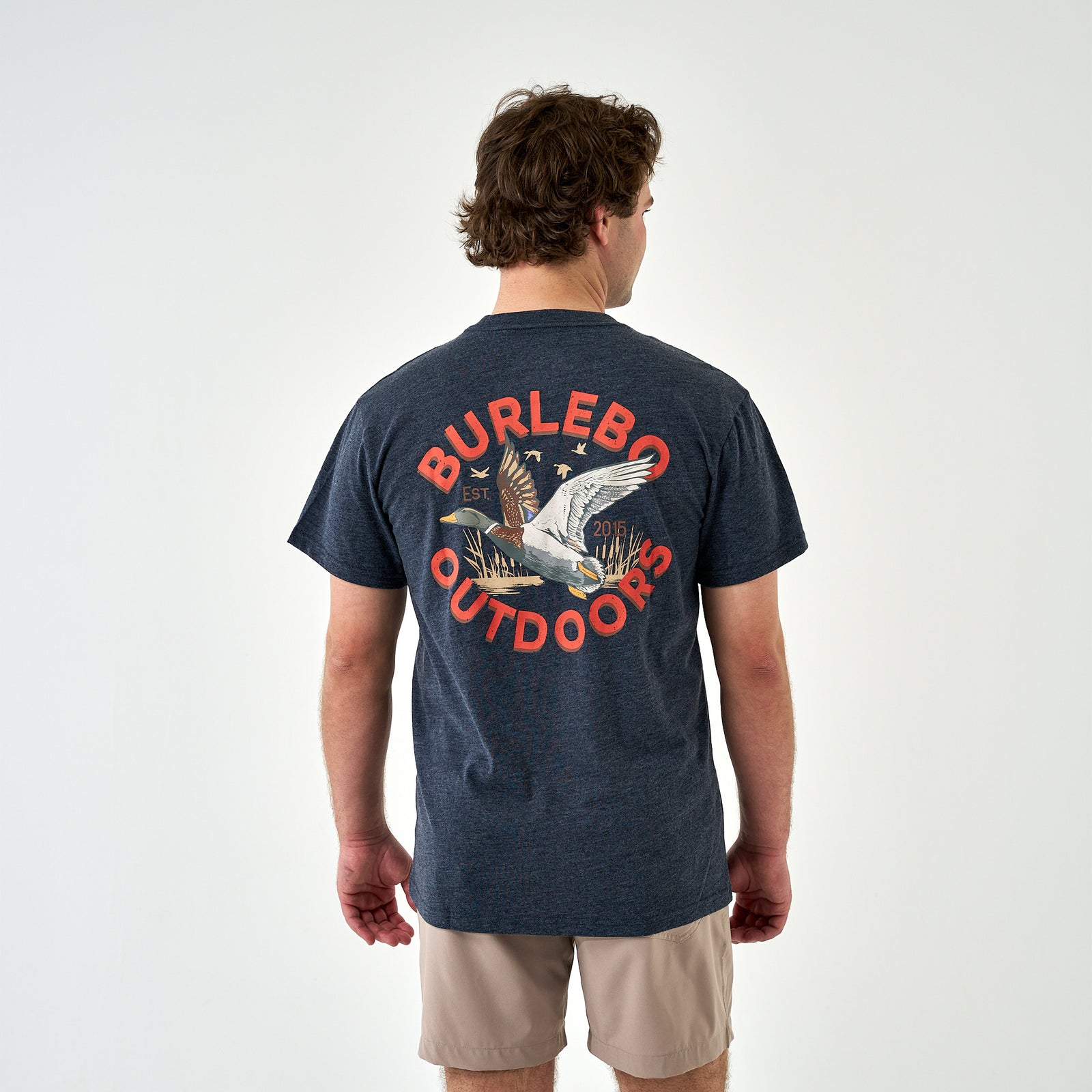 Back view of man wearing navy Burlebo Outdoors t-shirt with flying duck graphic and red text.