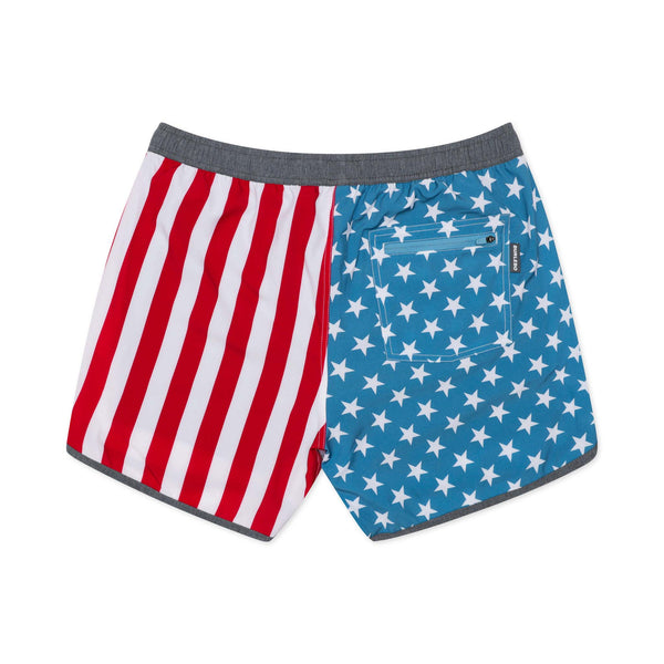 Burlebo Men's Swim Trunks in Throwback USA. Sizes S-XXL. Back view of trunks laid flat showing blue star pattern on one side and red and white vertical stripes on the other, with zippered back pocket.