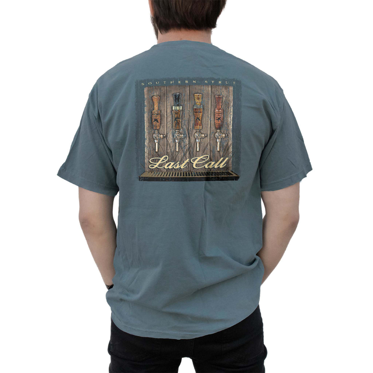 Back view of a blue t-shirt with a “Southern Strut Last Call” design showing five decorative beer tap handles against a wooden background.