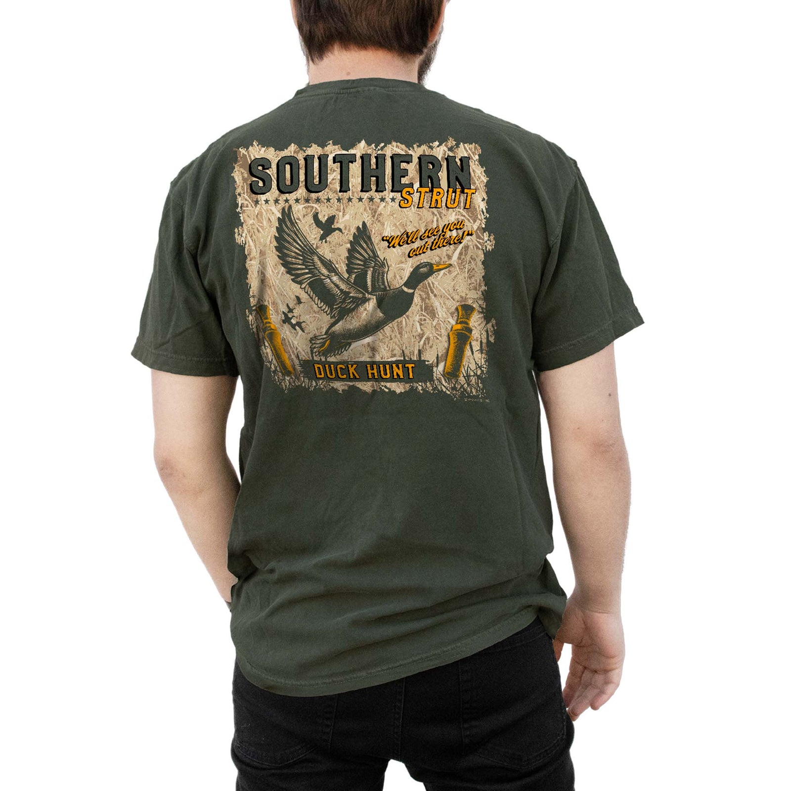 Southern Strut Duck Hunt t-shirt in moss green with flying duck hunting graphic and "We’ll see you out there" text on back.
