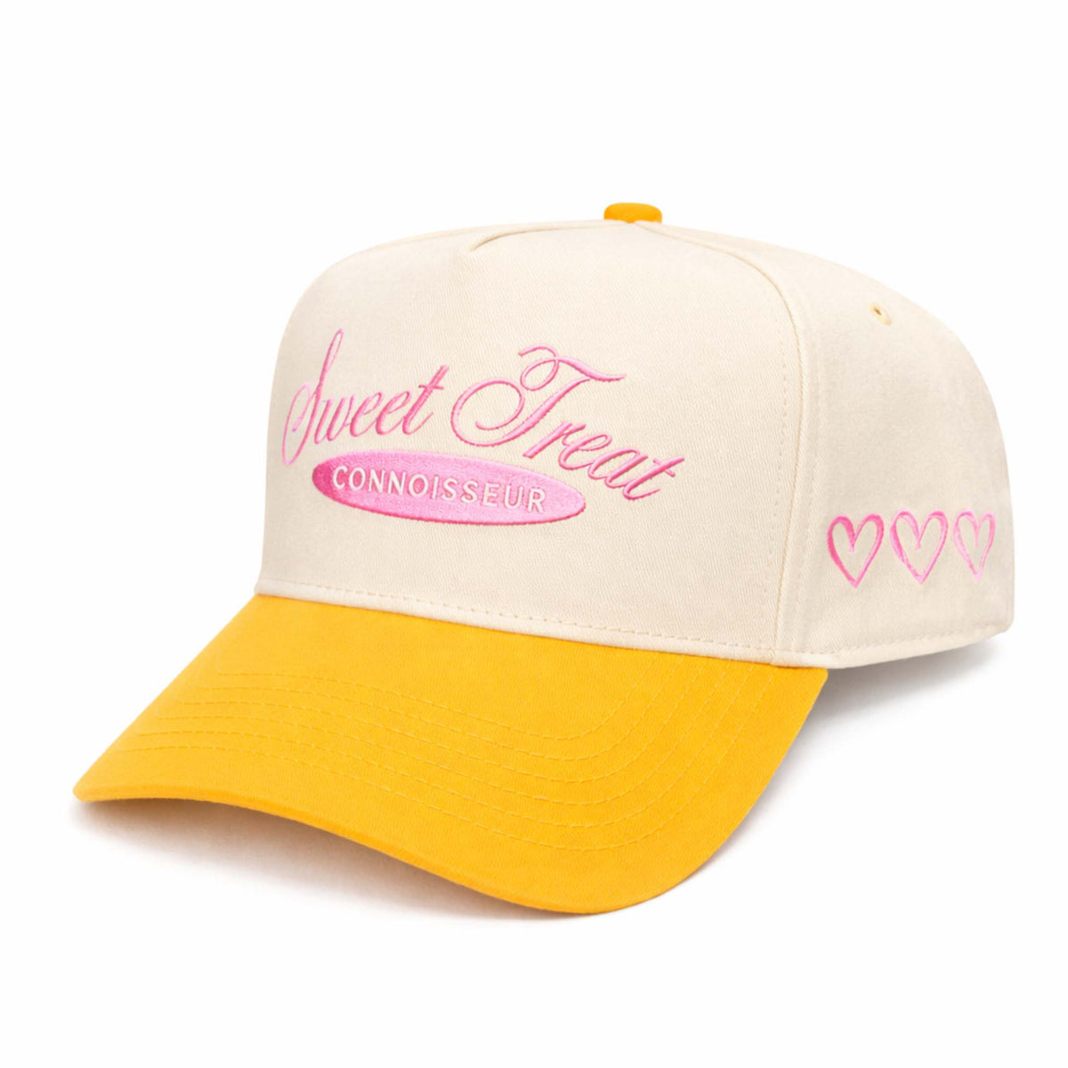 Cream and orange baseball hat with pink embroidered “Sweet Treat Connoisseur” text on the front and pink heart details stitched on the side panel.