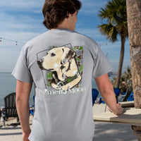 Palmetto Moon men’s light gray short sleeve t-shirt with Labrador dog graphic on back, shown outdoors by the beach.