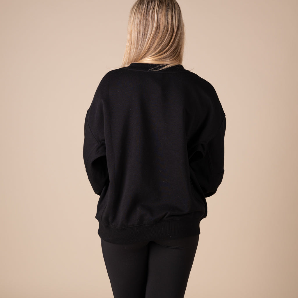 Person wearing a black sweatshirt against a beige background