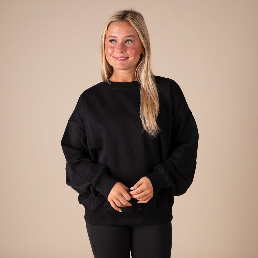 Person wearing a black sweatshirt against a beige background