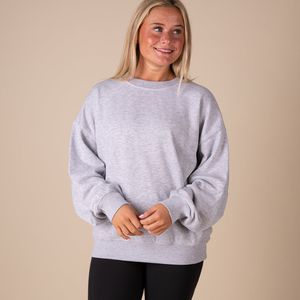 Woman wearing a gray sweatshirt against a beige background