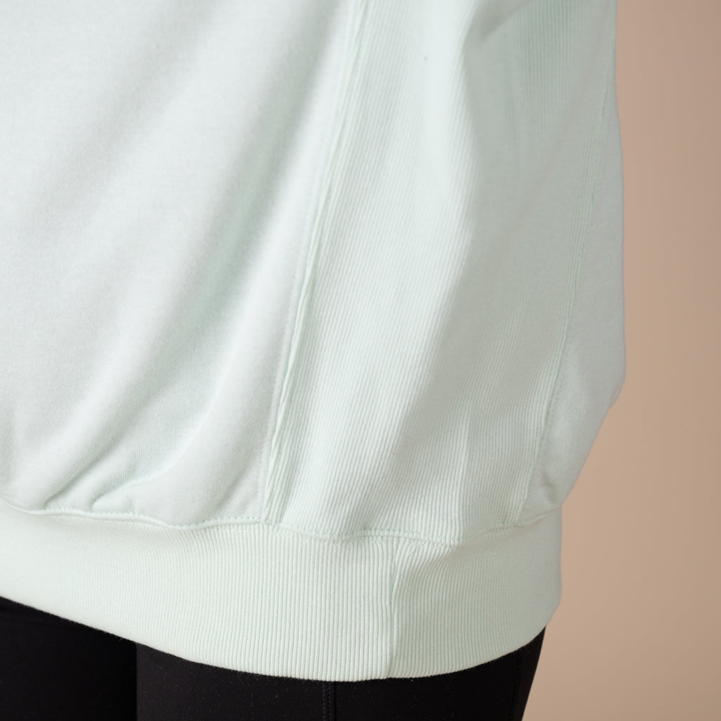 Close-up of a light green sweatshirt on a beige background