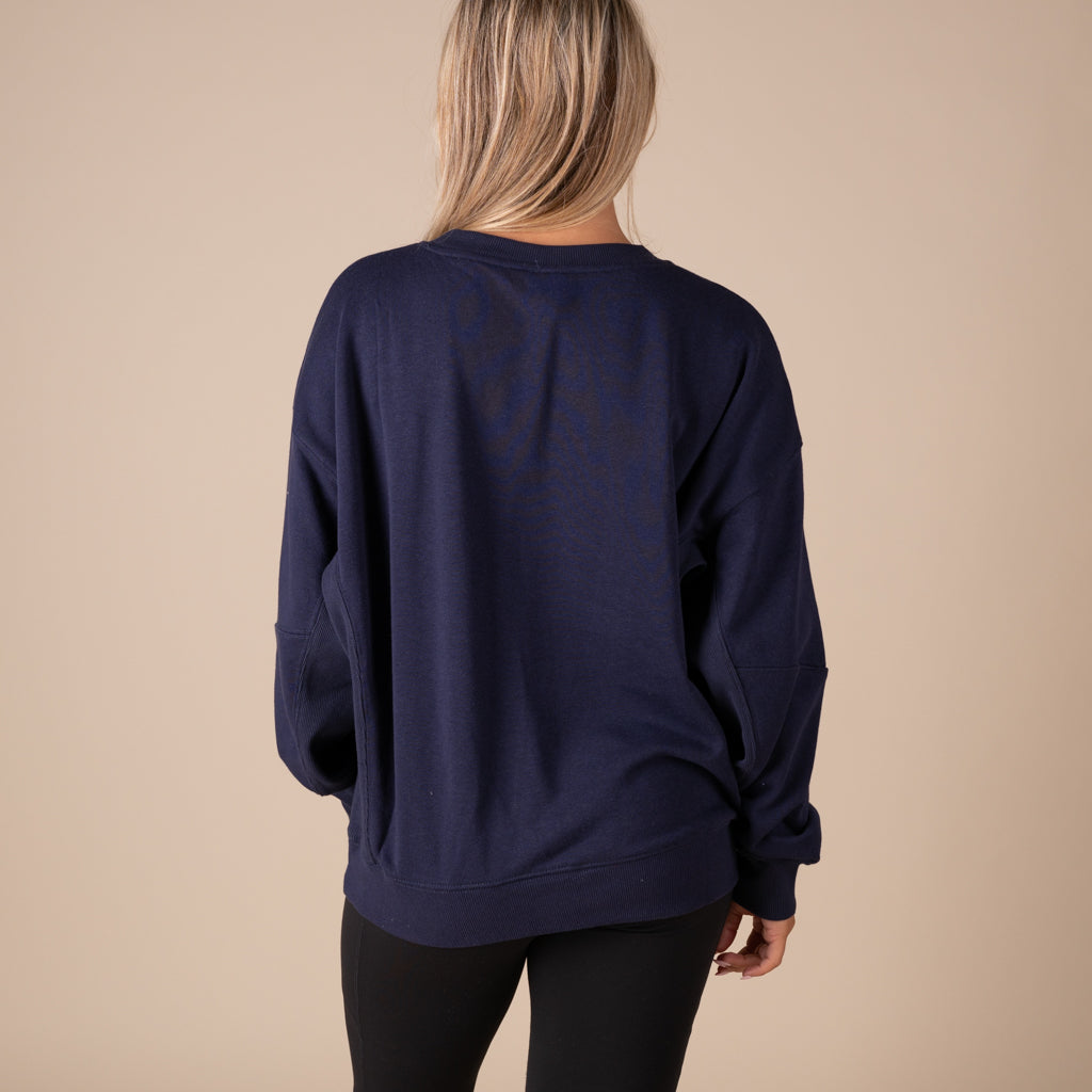 Person wearing a navy blue sweatshirt against a beige background