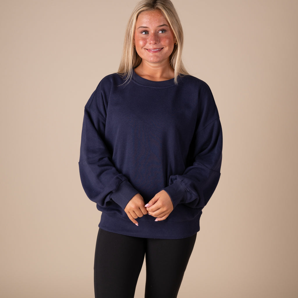 Woman wearing a navy blue sweatshirt against a beige background