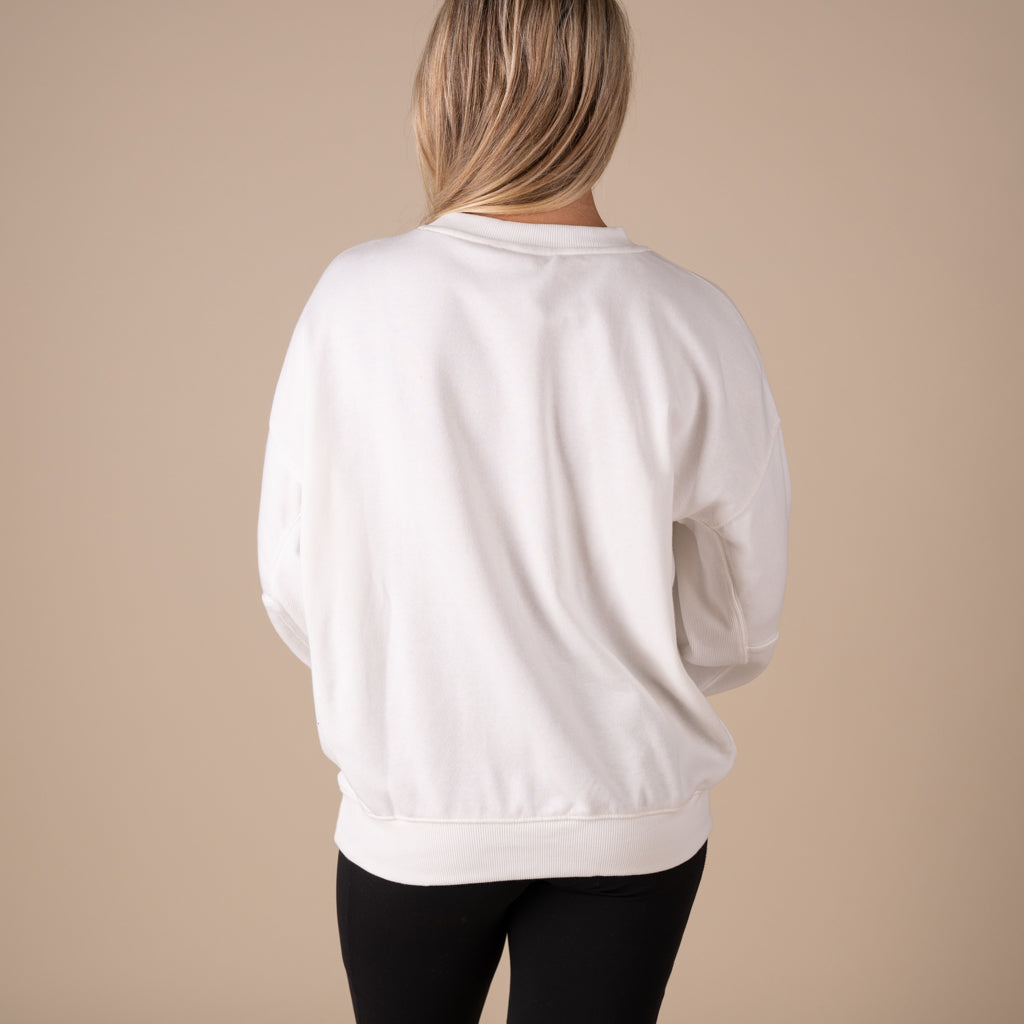 Person wearing a white sweatshirt against a beige background