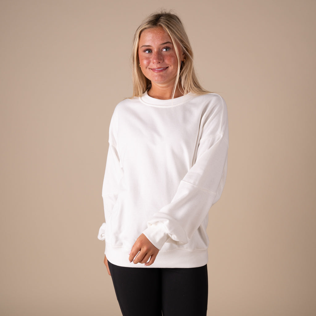 Woman wearing a white sweatshirt against a beige background