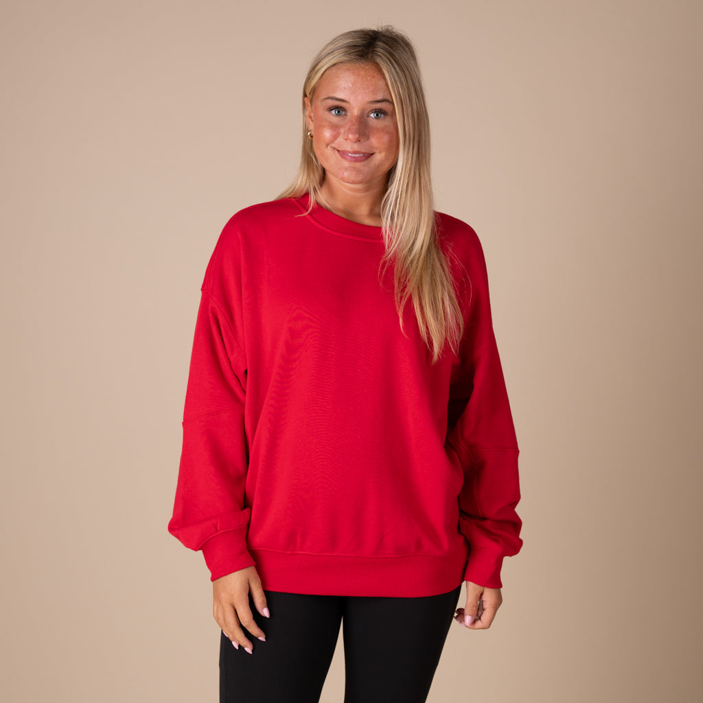 Woman wearing a red sweatshirt against a beige background