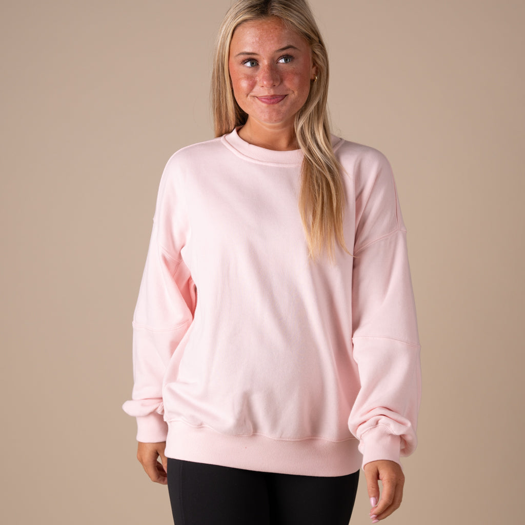 Woman wearing a pink sweatshirt against a beige background
