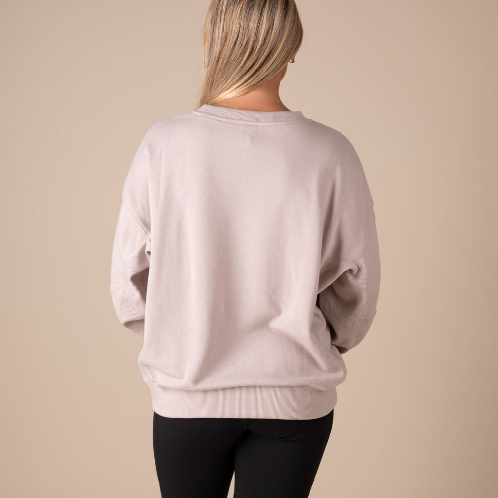 Person wearing a light pink sweatshirt against a beige background