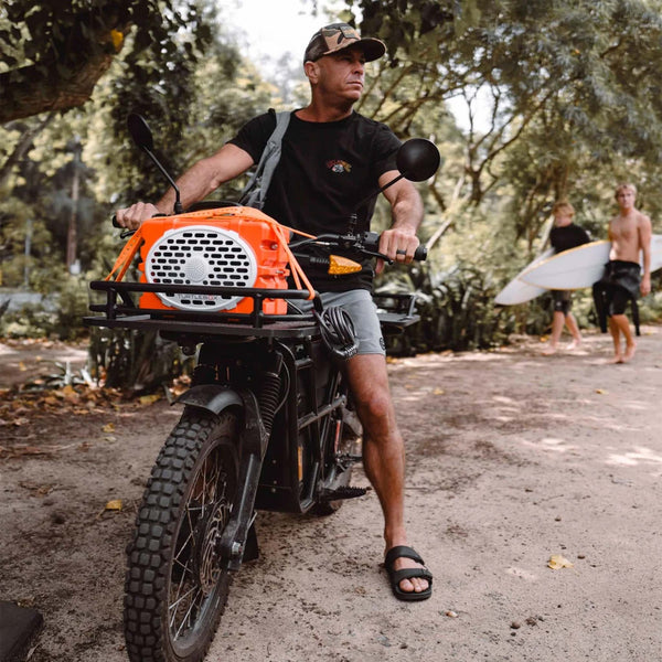 Man riding an electric bike with an orange generation 3 Turtlebox strapped to the front of the bike.